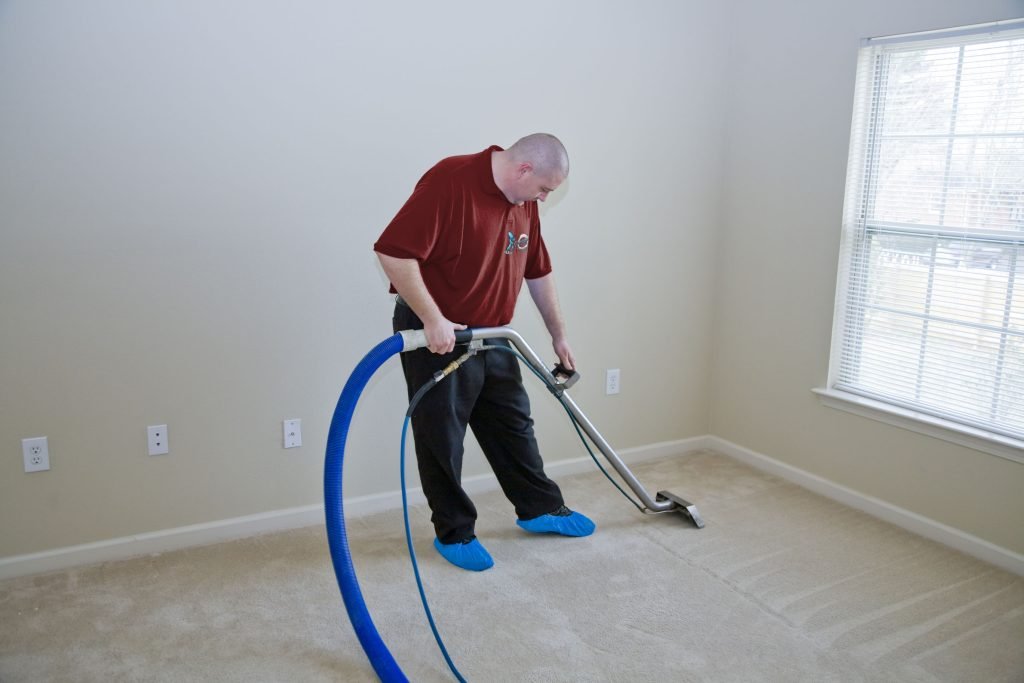 Professional cleaner using carpet cleaning equipment in a bright, empty room, emphasizing house cleaning services in Melbourne.