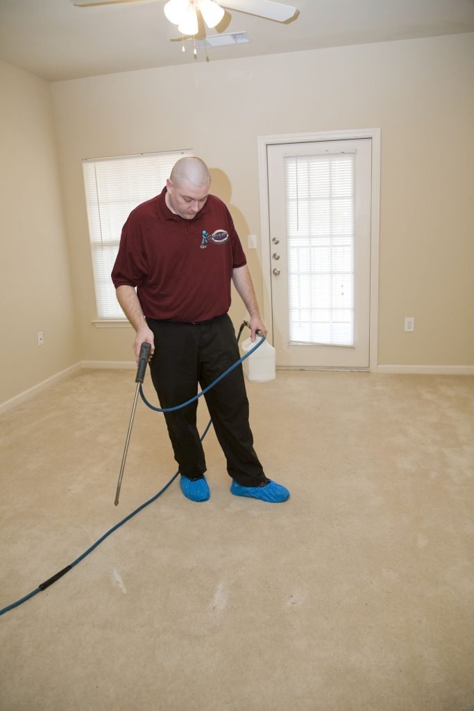 Professional cleaner using equipment in empty room, emphasizing child care cleaning services and thorough cleaning process.